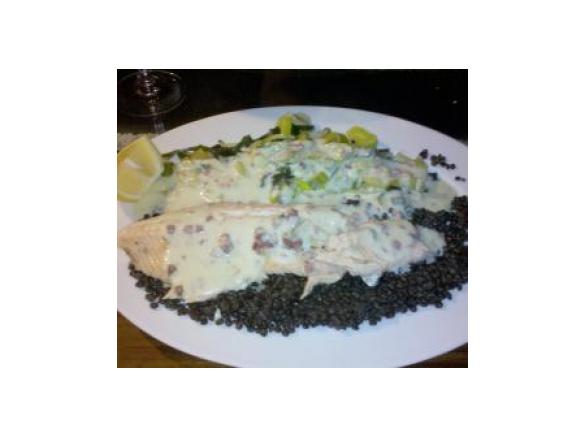 Forelle auf schwarzen Linsen mit Lauch